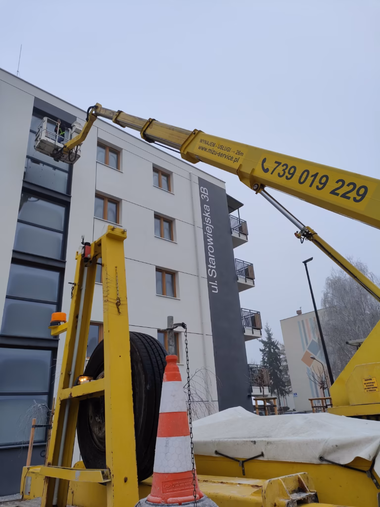 man 27 metrów rozłożony przy myciu okien na znacznej wysokości bloku mieszkalnego Podnośnik Ruthmann przy myciu okien bloku mieszkalnego zimą
